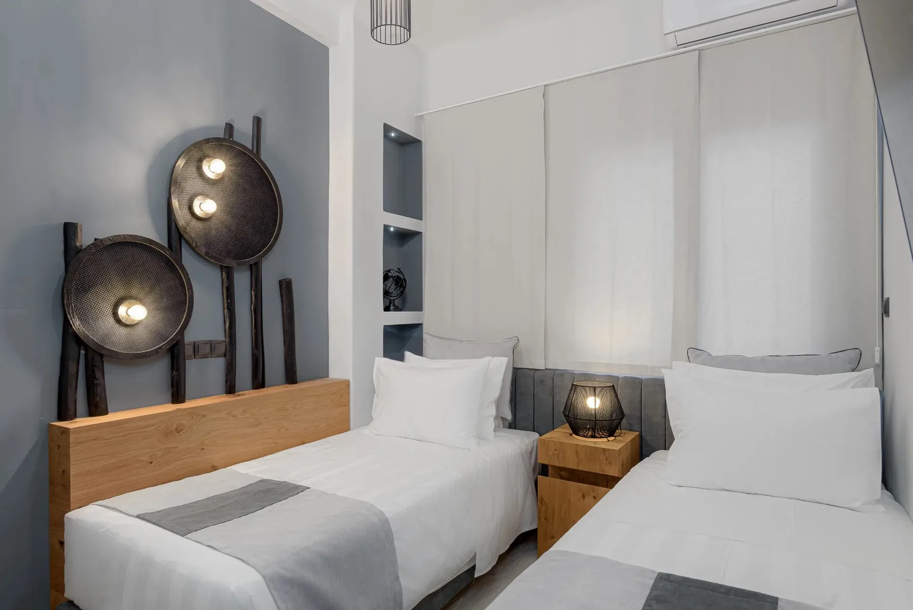 A bedroom with two beds and a wooden bedside table.