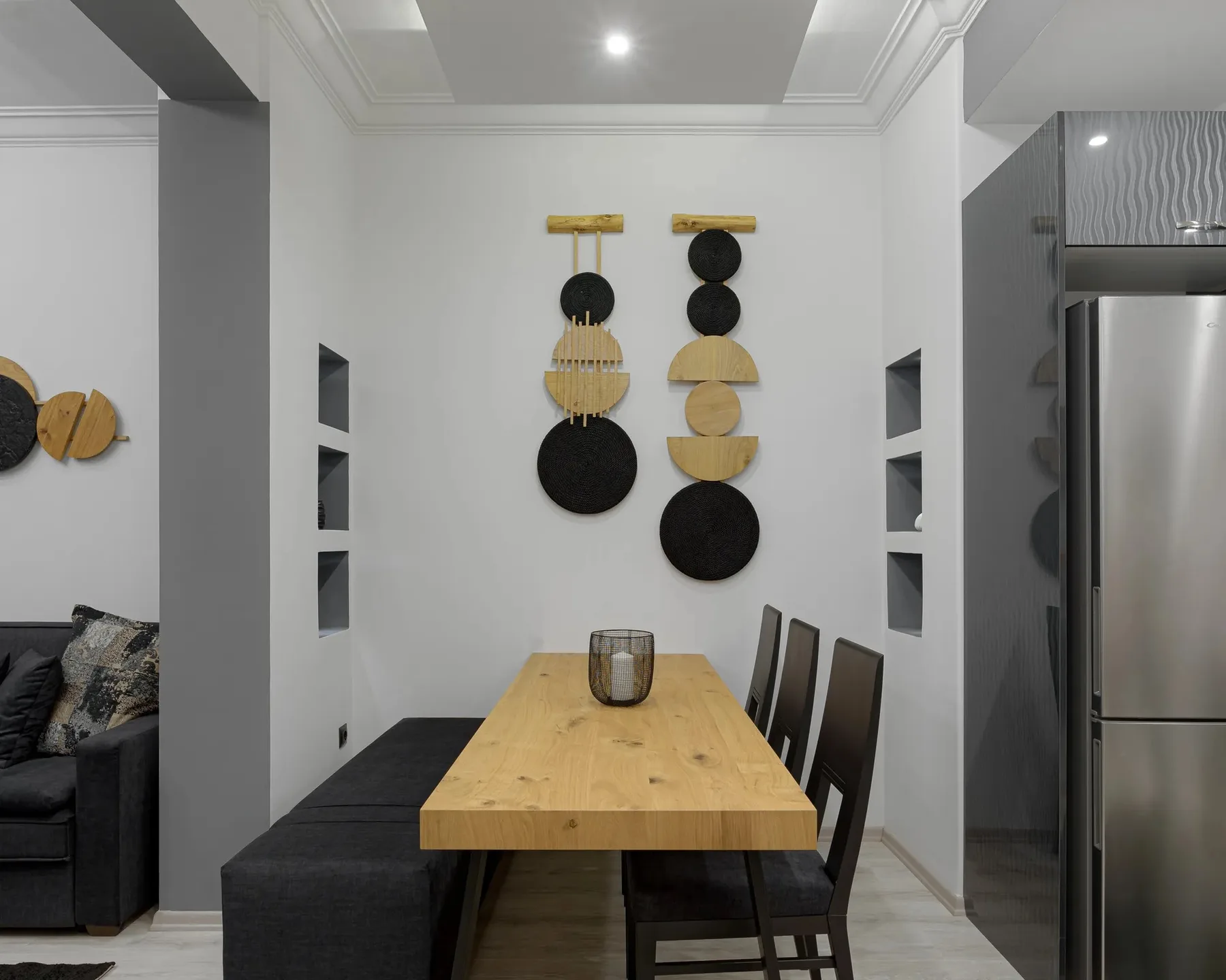 A dining area with a wooden table, dark seating, and circular wall decorations.