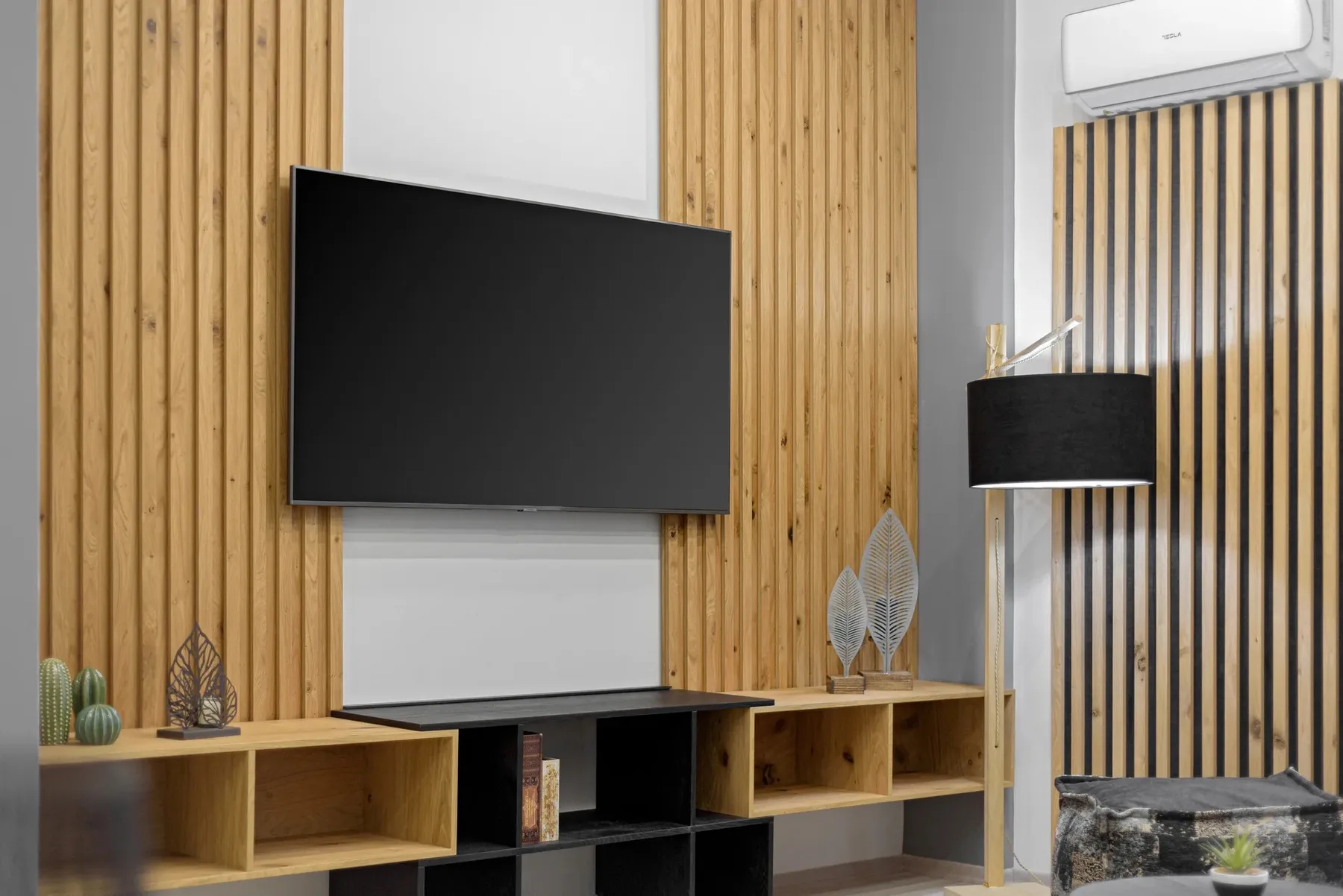 A living room features a wall-mounted television and wooden shelving.