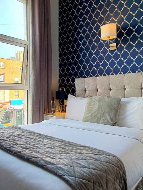 Habitación de hotel con una cama y decoración en azul y dorado.