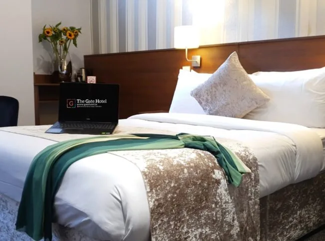 Habitación de hotel con una cama doble y flores junto a la cama.