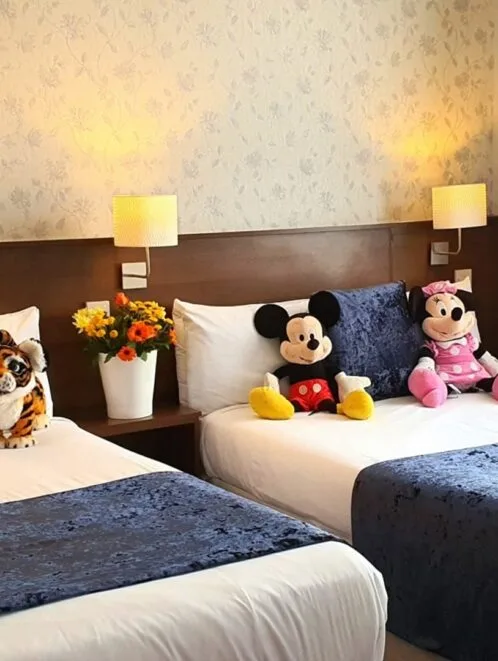 Habitación de hotel con dos camas dobles y papel tapiz floral.