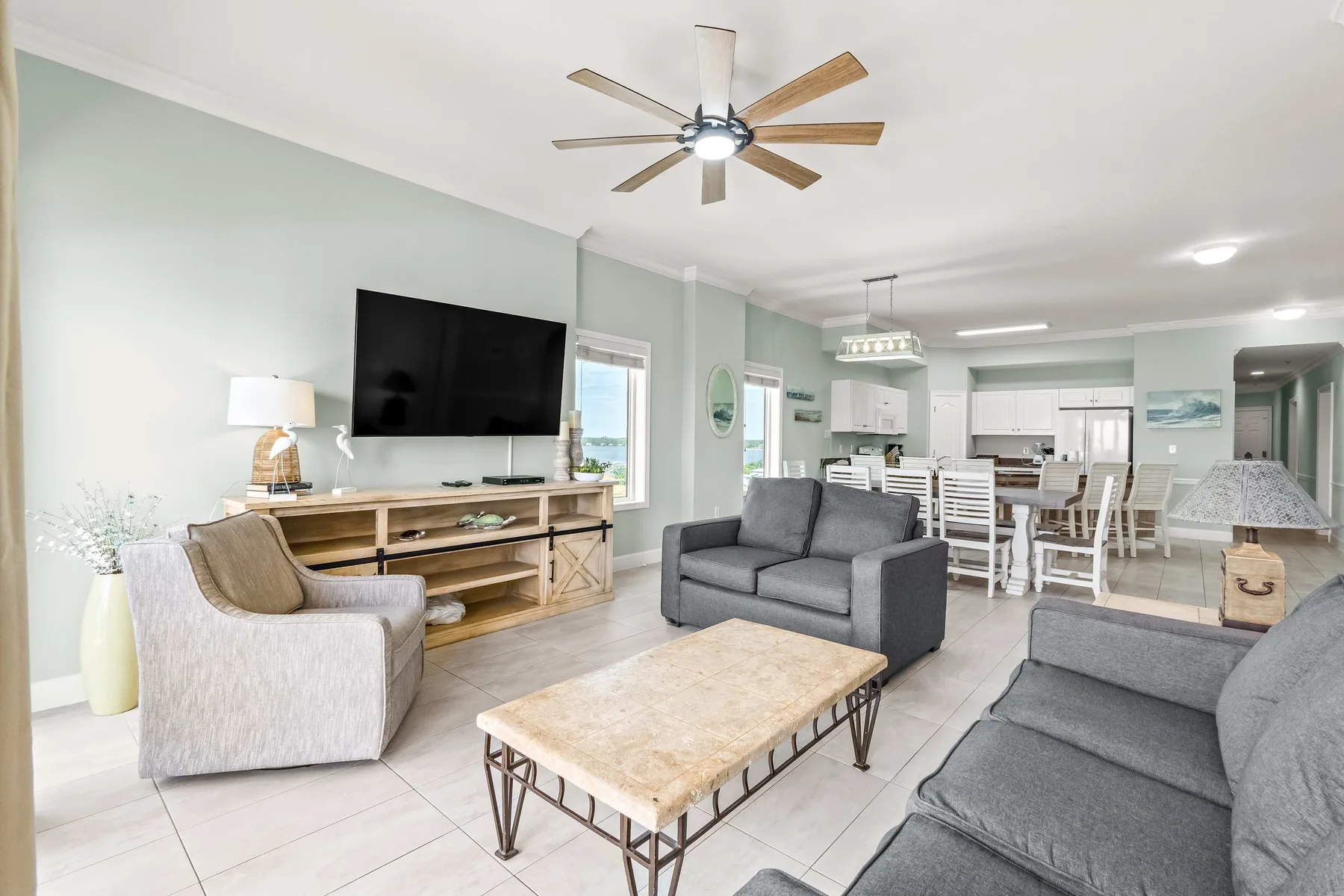 A living room with gray seating and a coffee table opens into a dining area.