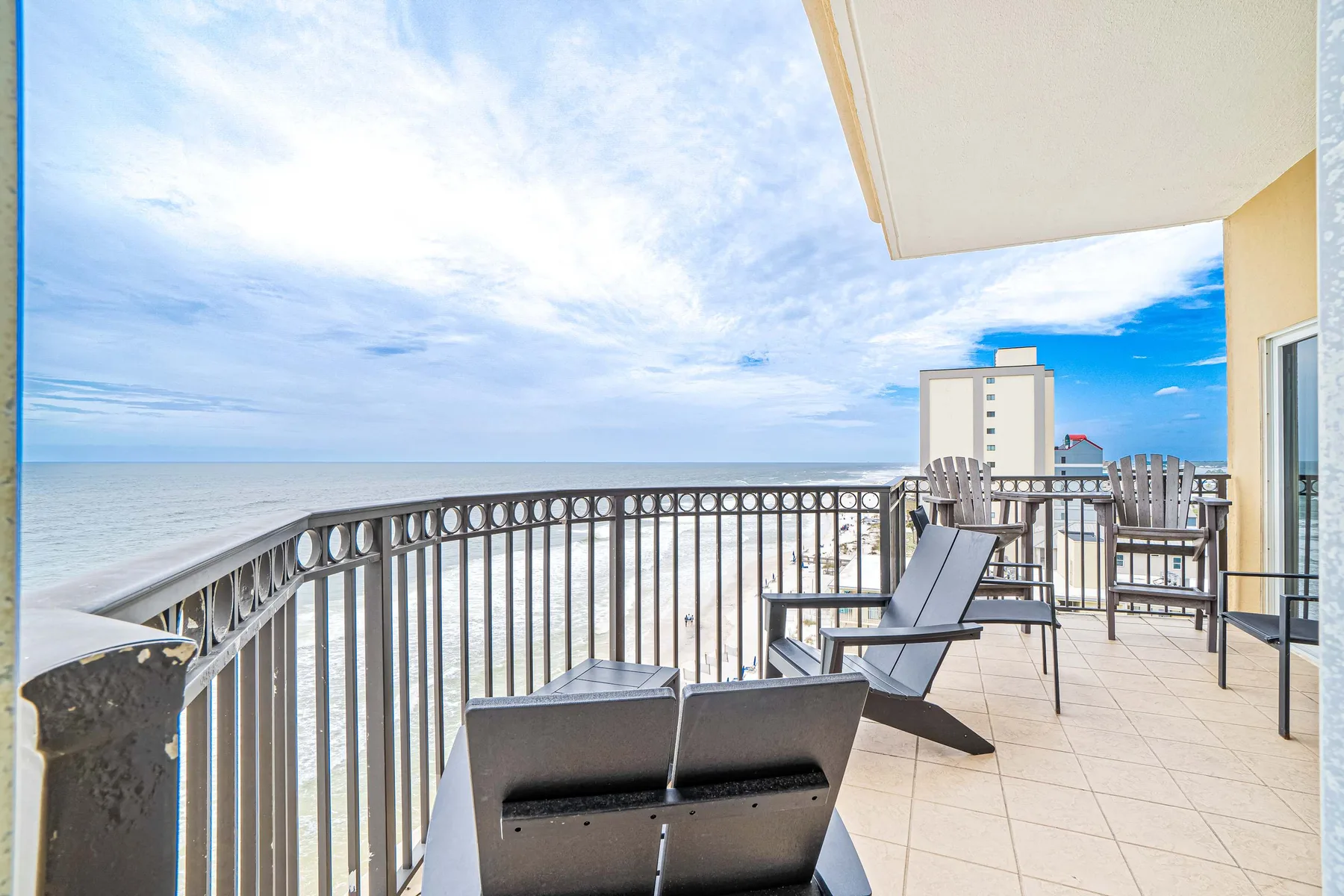 A balcony with seating overlooks the beach and ocean.