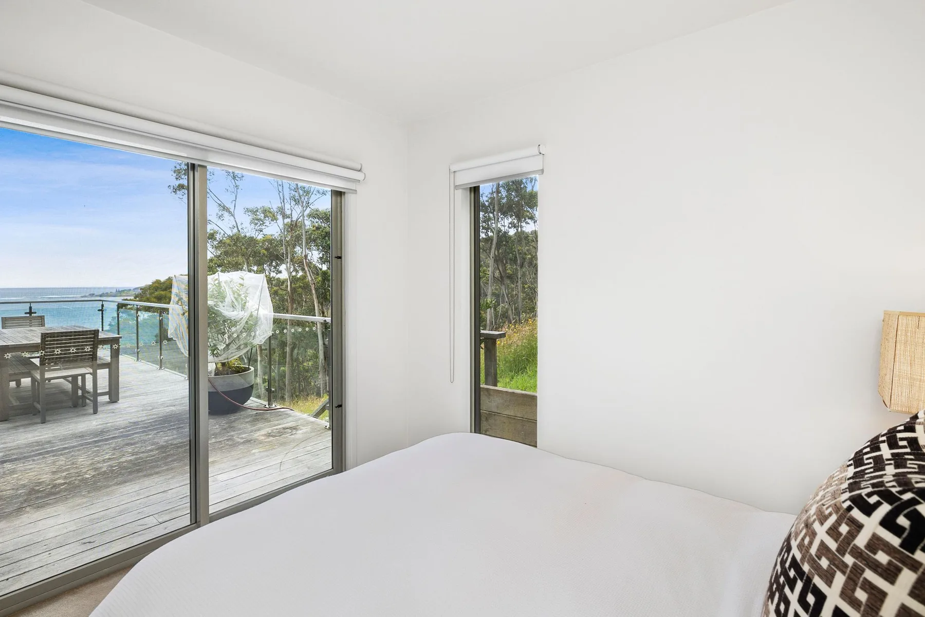 Dormitorio con una cama junto a puertas de vidrio que dan a una terraza con vistas al agua.