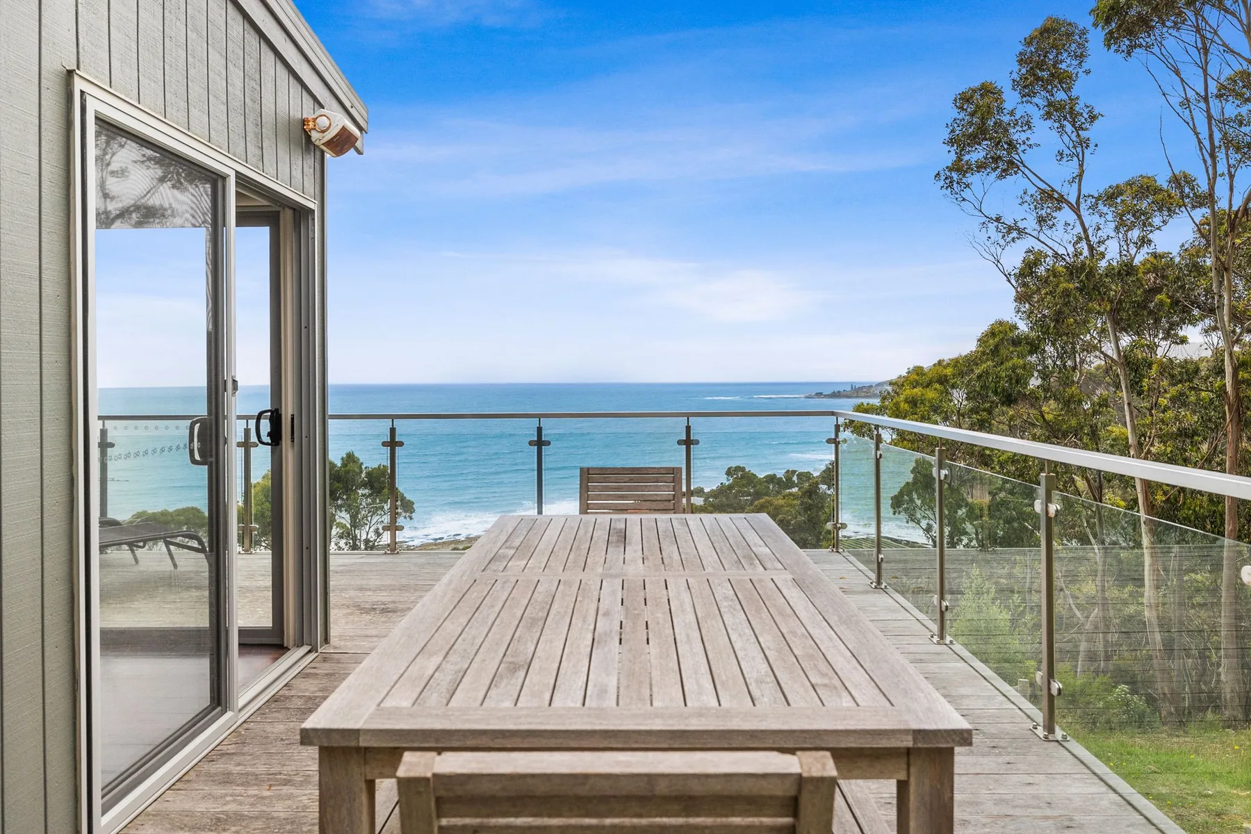 Una terraza al aire libre con una mesa de madera frente al mar.
