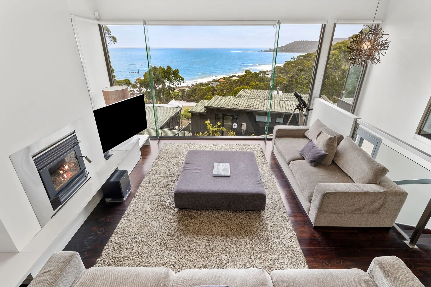 Una sala de estar con asientos y una ventana amplia con vistas a la costa.