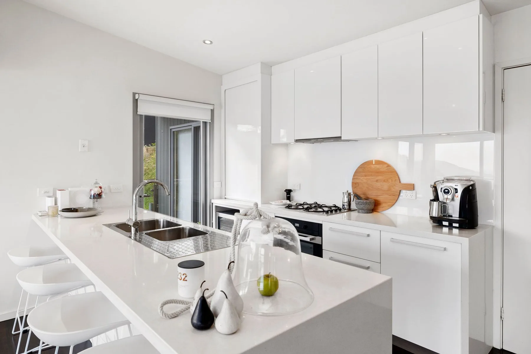 Una cocina moderna y luminosa con gabinetes blancos y una isla amplia.