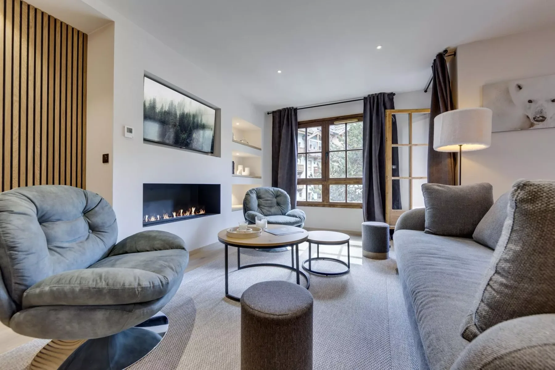 A living room with cushioned seating, a fireplace, and a large window.