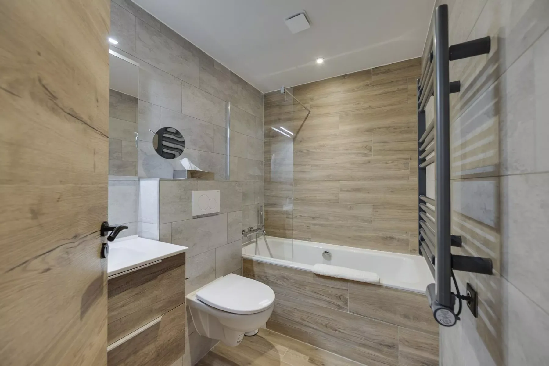 A tiled bathroom with a bathtub, toilet, and sink.
