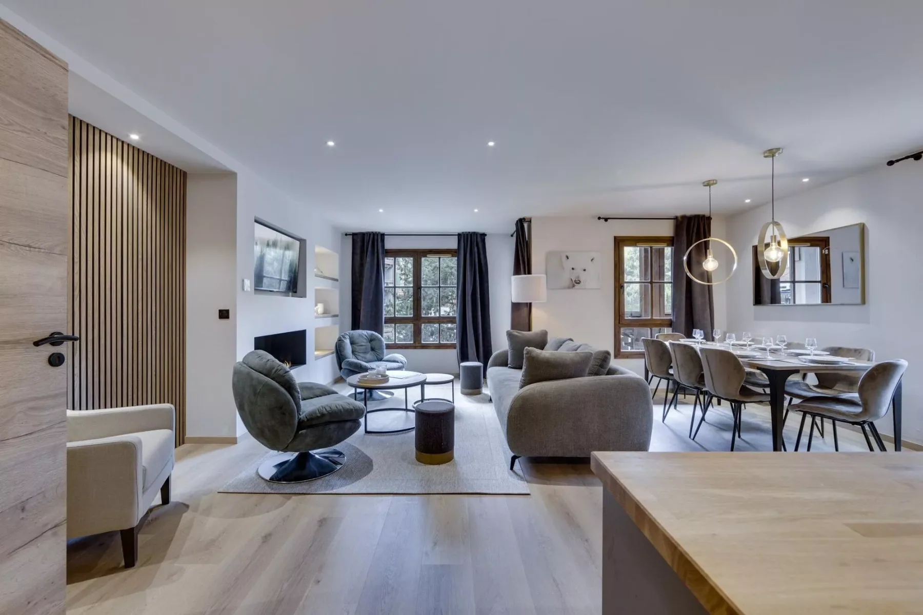 An open-plan living and dining room with seating, a dining table, and large windows.