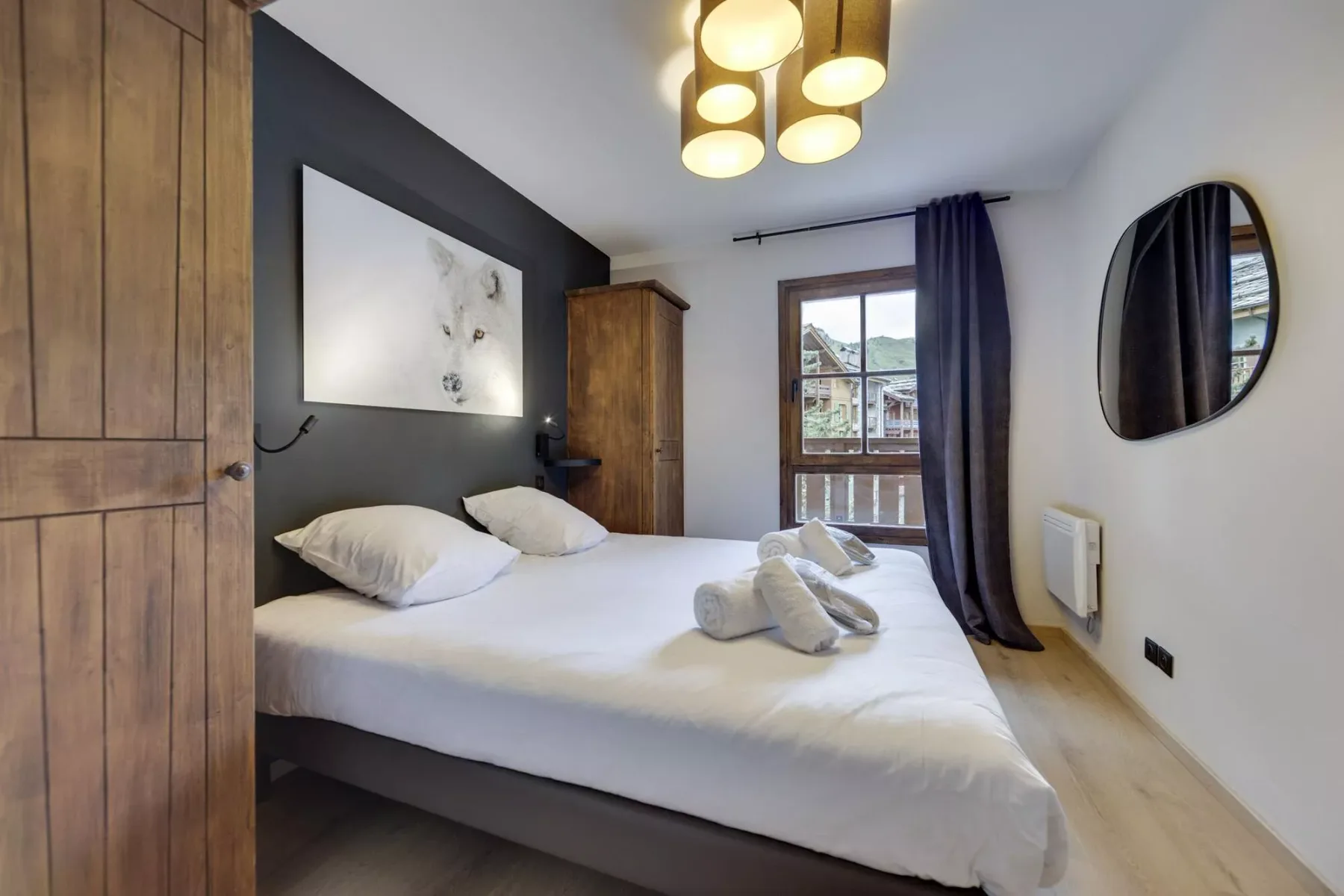 A bedroom with a neatly made bed and a window framed by dark curtains.