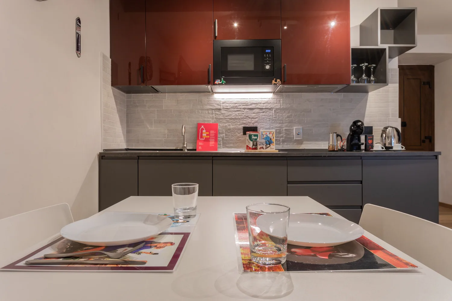 A modern kitchen with a dining table set with plates and glasses.