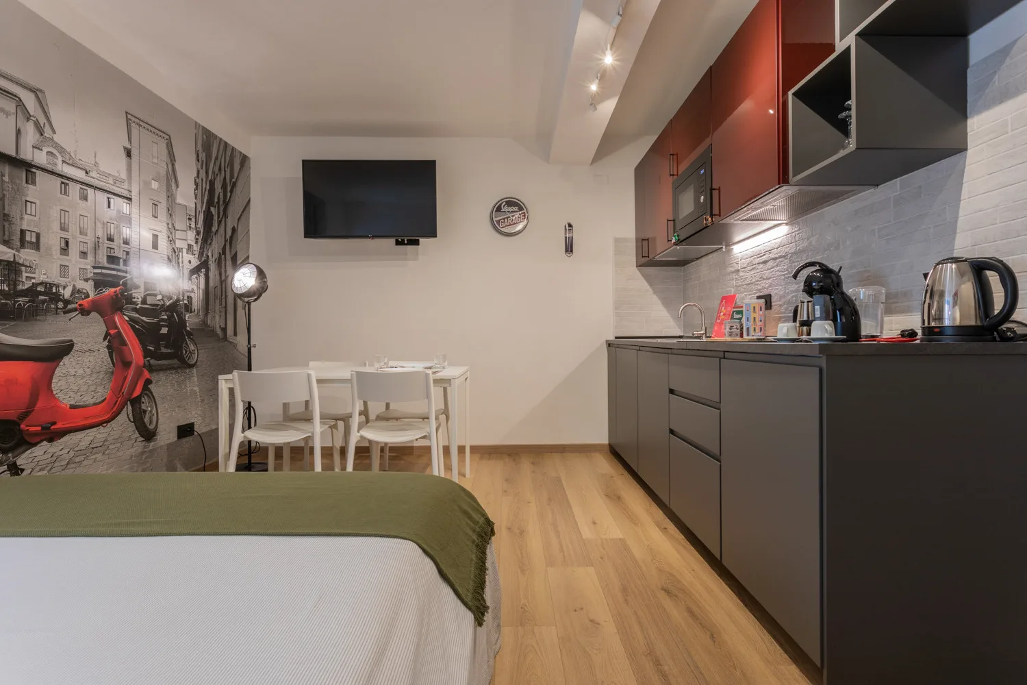 A compact room combines a bed, dining table, and kitchenette.