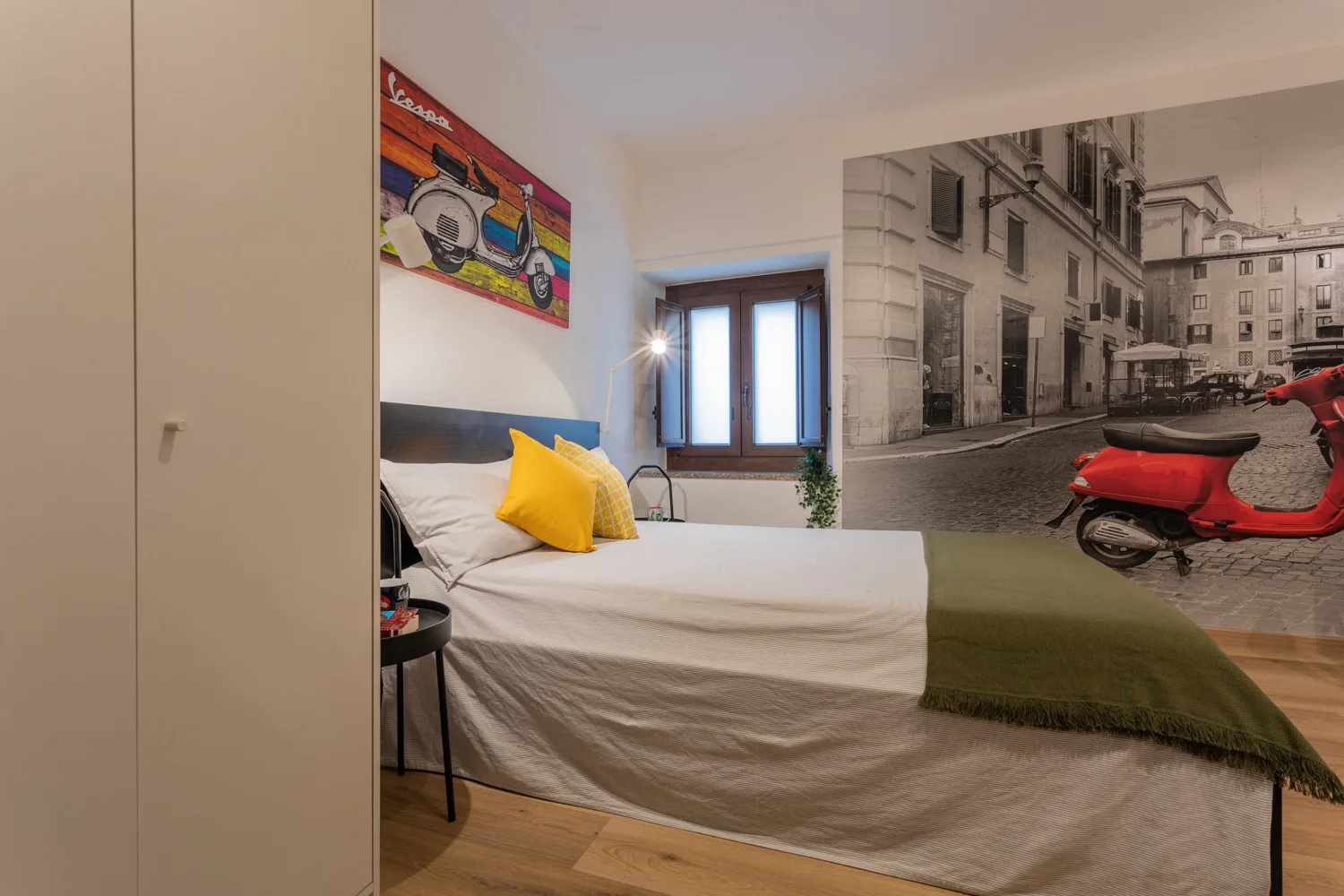 A bedroom with a bed, yellow pillows, and a mural of a street scene.