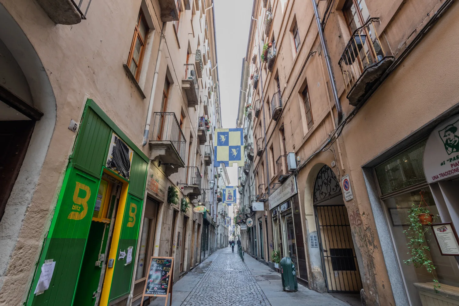 A narrow city street lined with tall buildings and storefronts.
