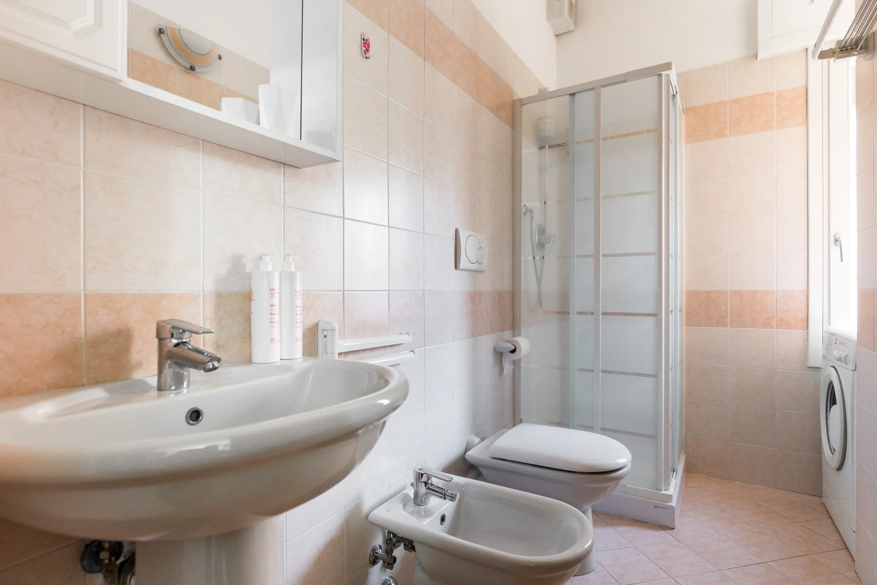 A tiled bathroom with a sink, toilet, bidet, and shower.