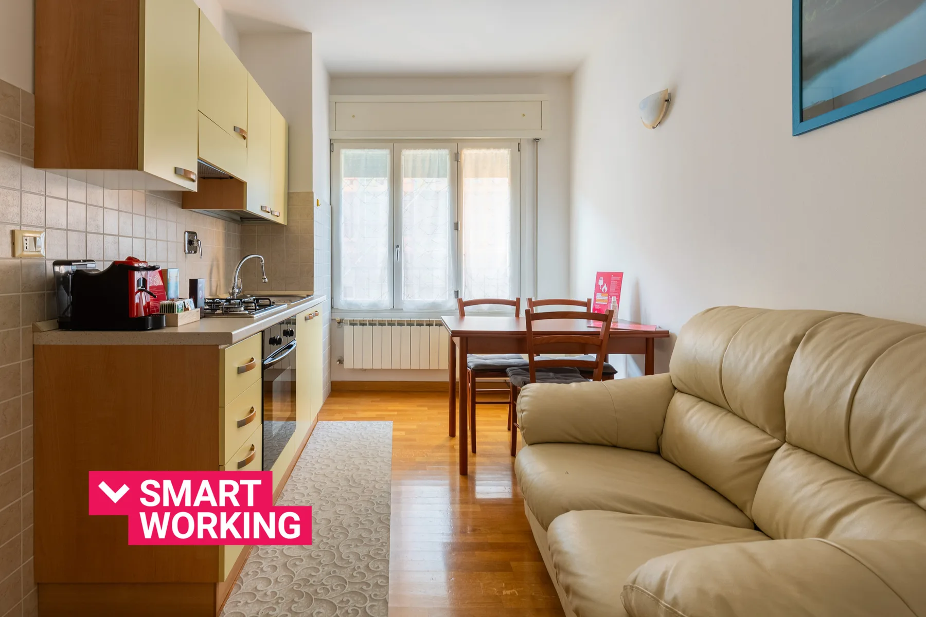 A living room with a dining table beside a compact kitchen and a sofa.