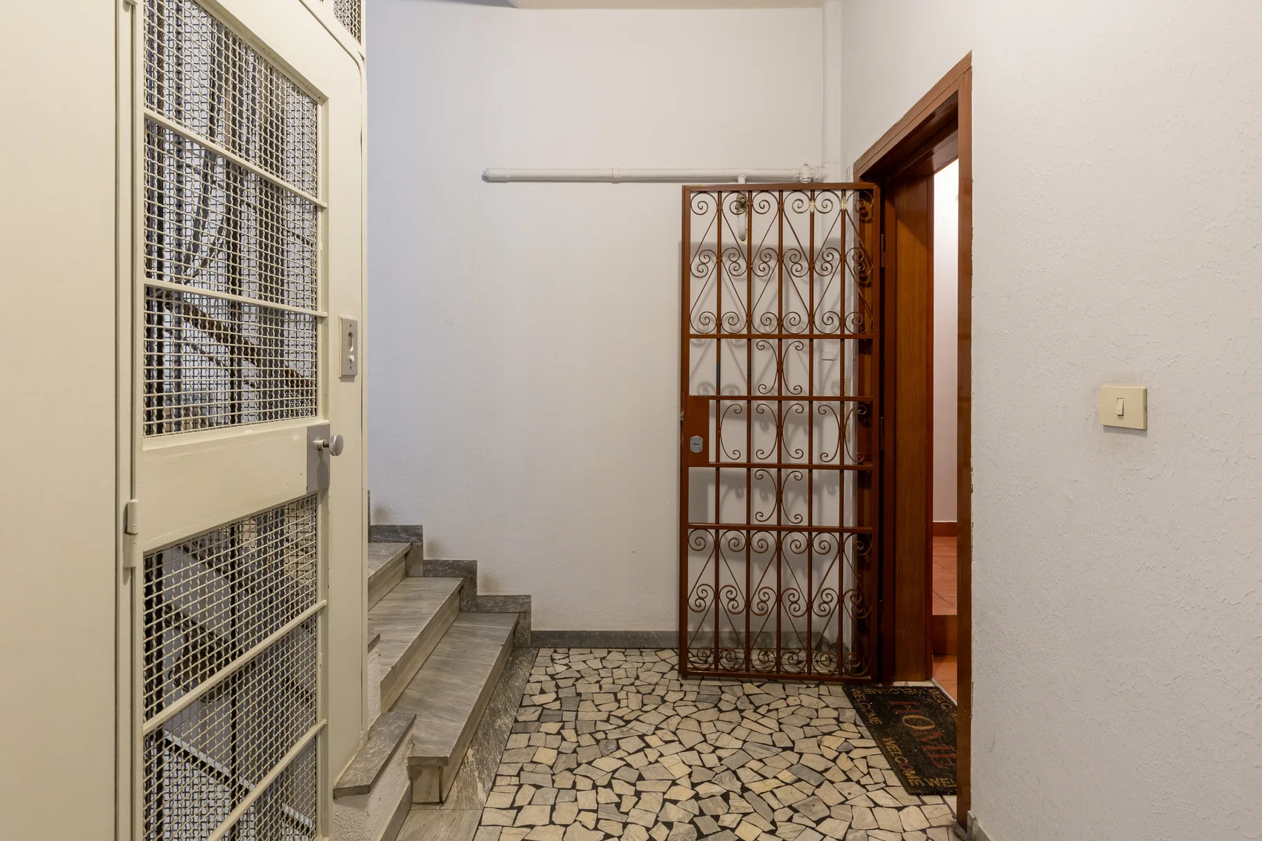 An indoor entryway with a decorative metal gate and tiled floor.