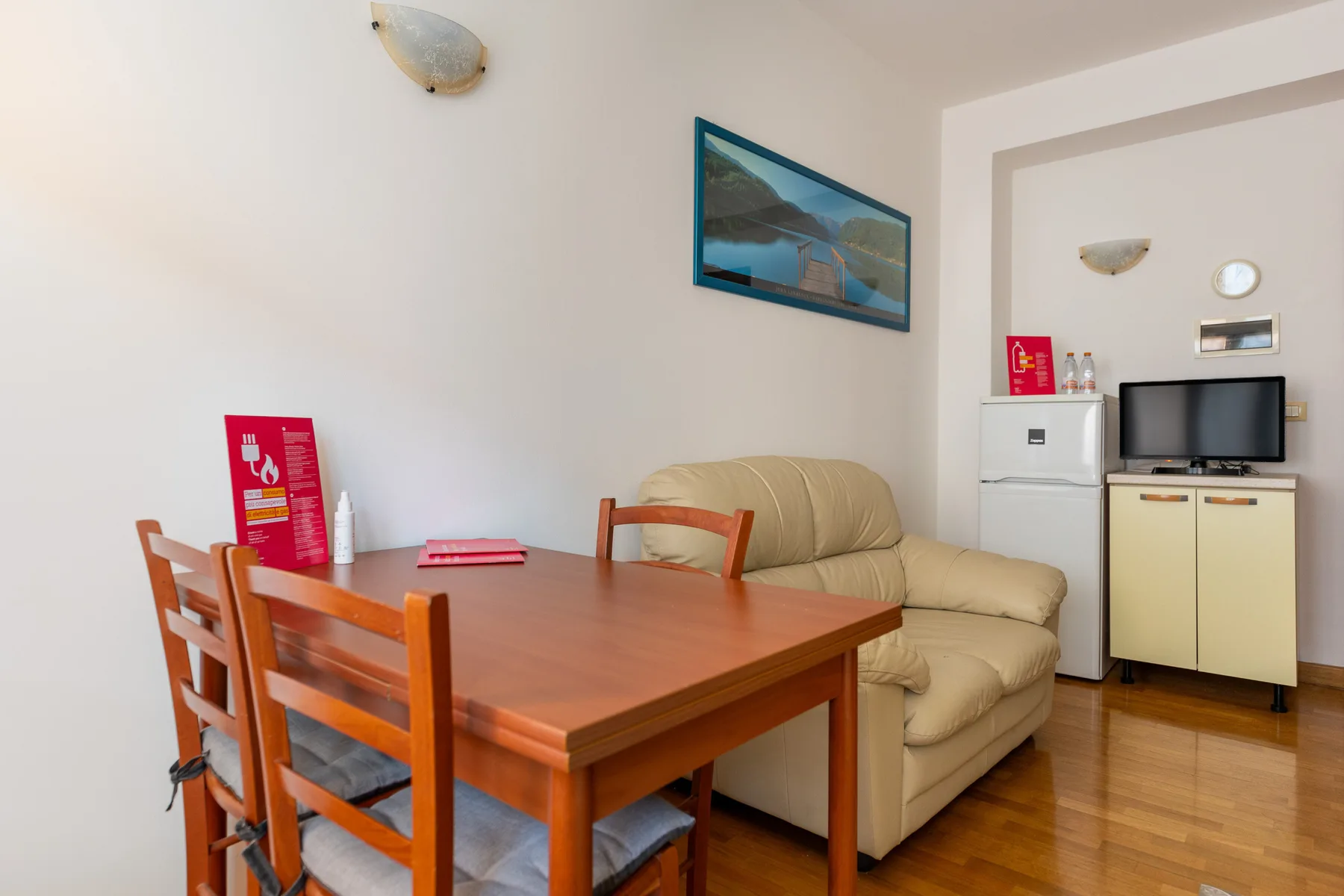 A dining table and chairs sit beside a beige sofa in a small room.