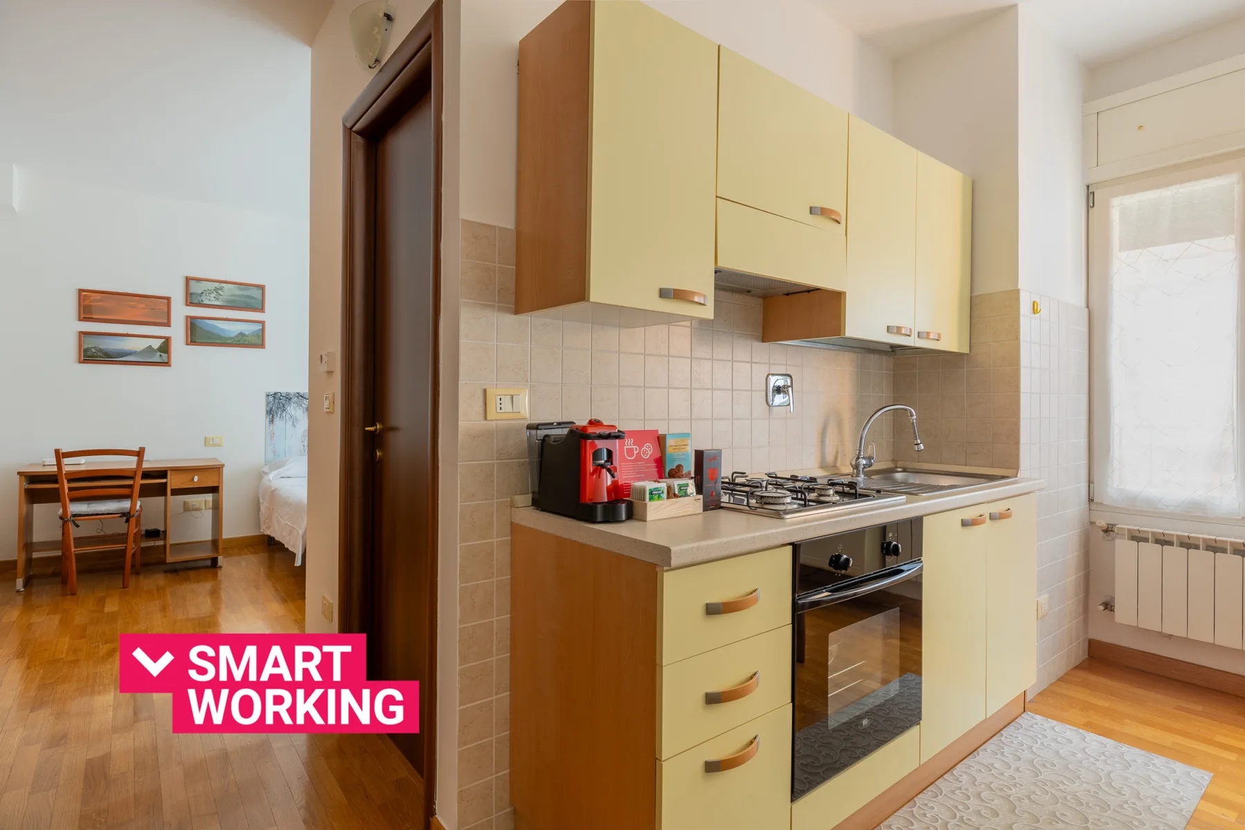 A compact kitchen with pale cabinets, a countertop, and a stove.