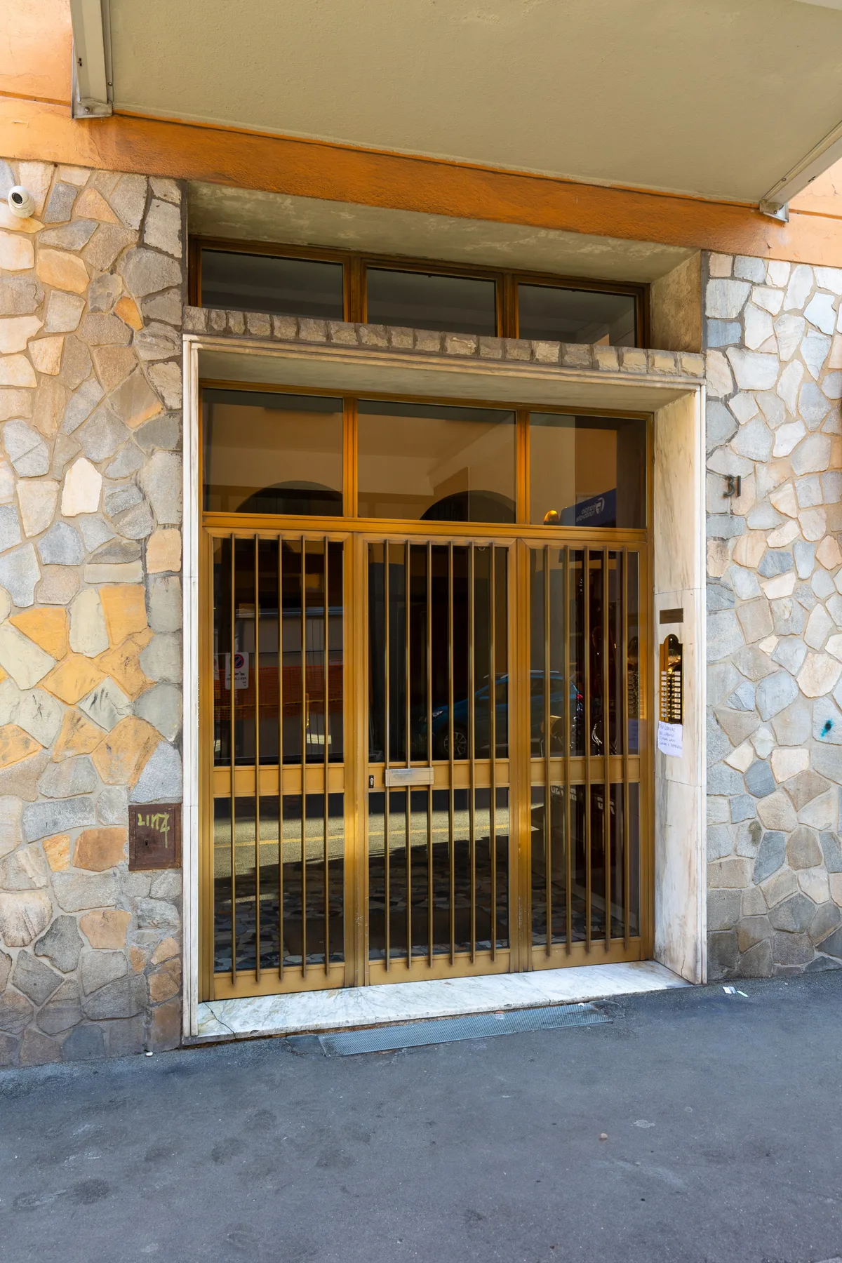 A building entrance with a metal security gate set in a stone facade.