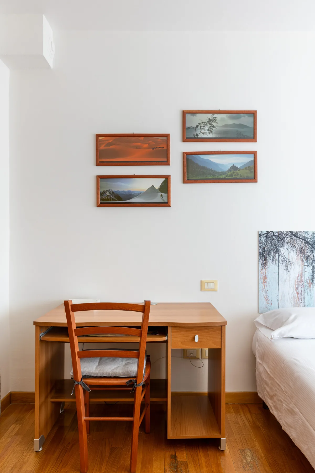 A bedroom with a wooden desk and chair beside a bed.