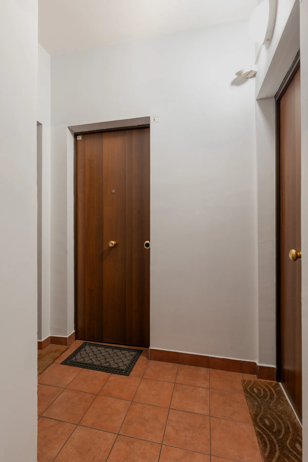 An interior hallway with brown doors and tiled flooring.