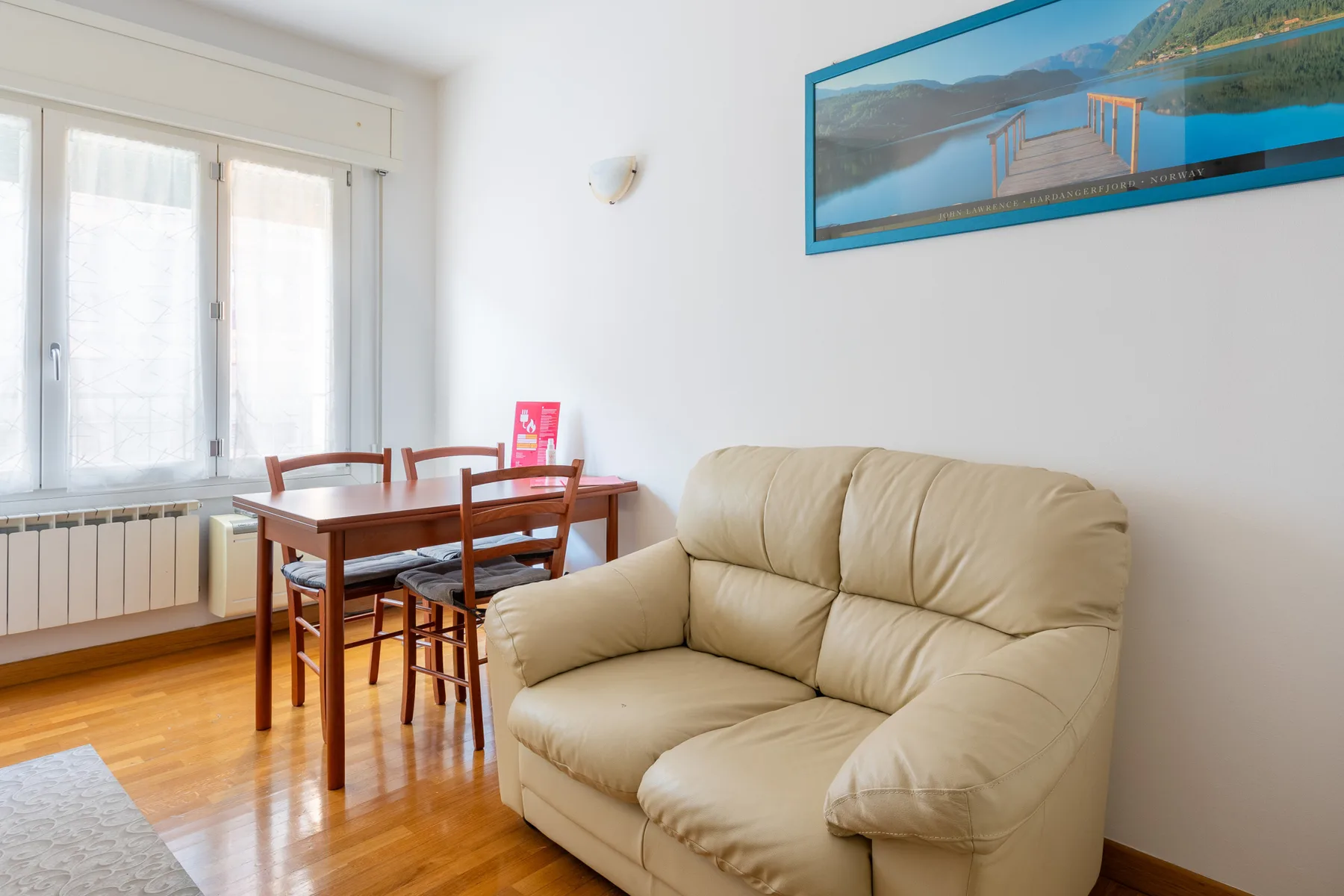 A living and dining area with a beige sofa and a wooden table.