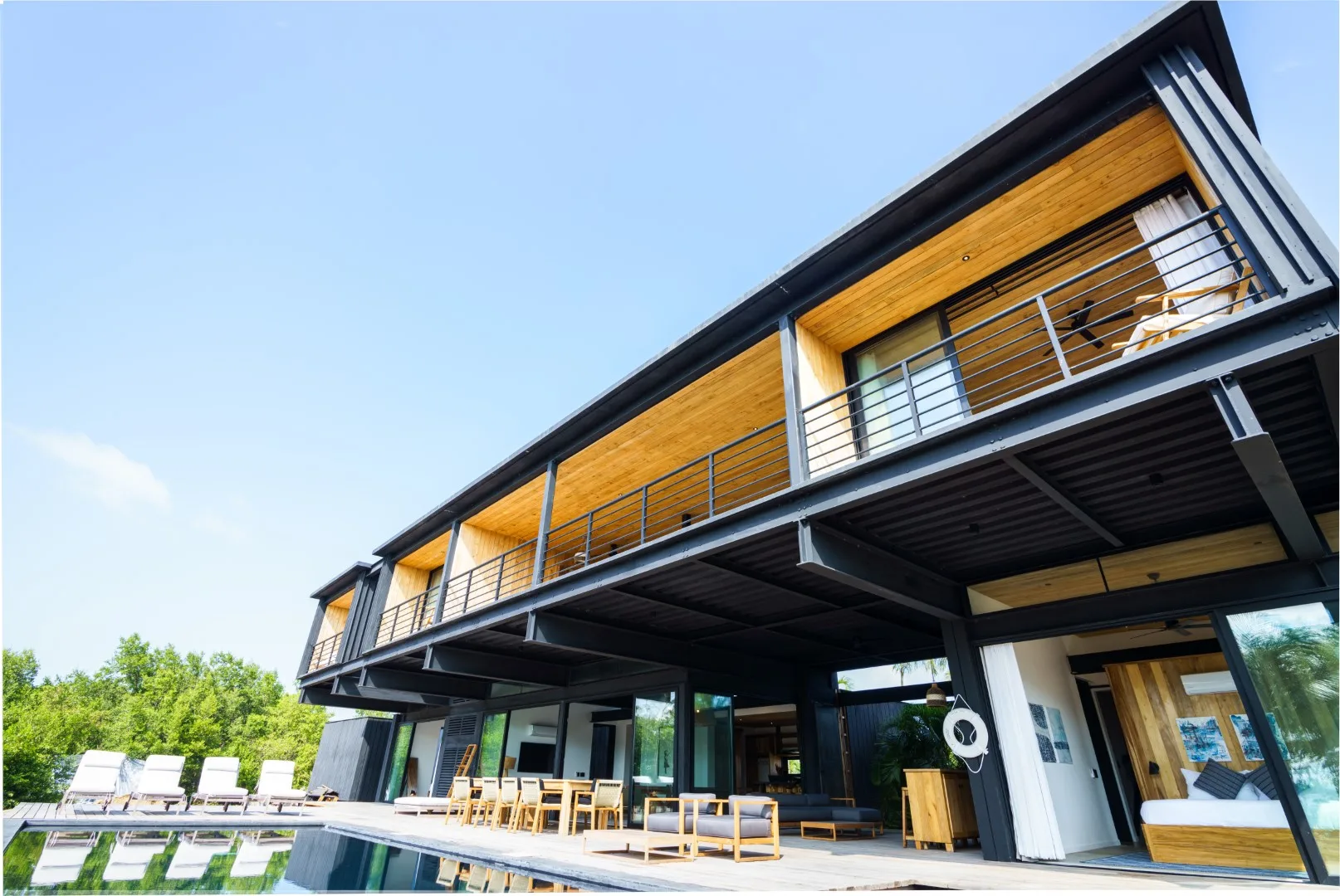 Exterior de una casa moderna con un largo balcón frente a una piscina.