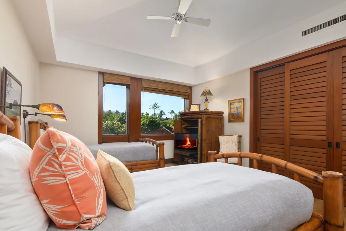 A bedroom with a bed, wooden shutters, and windows overlooking greenery.