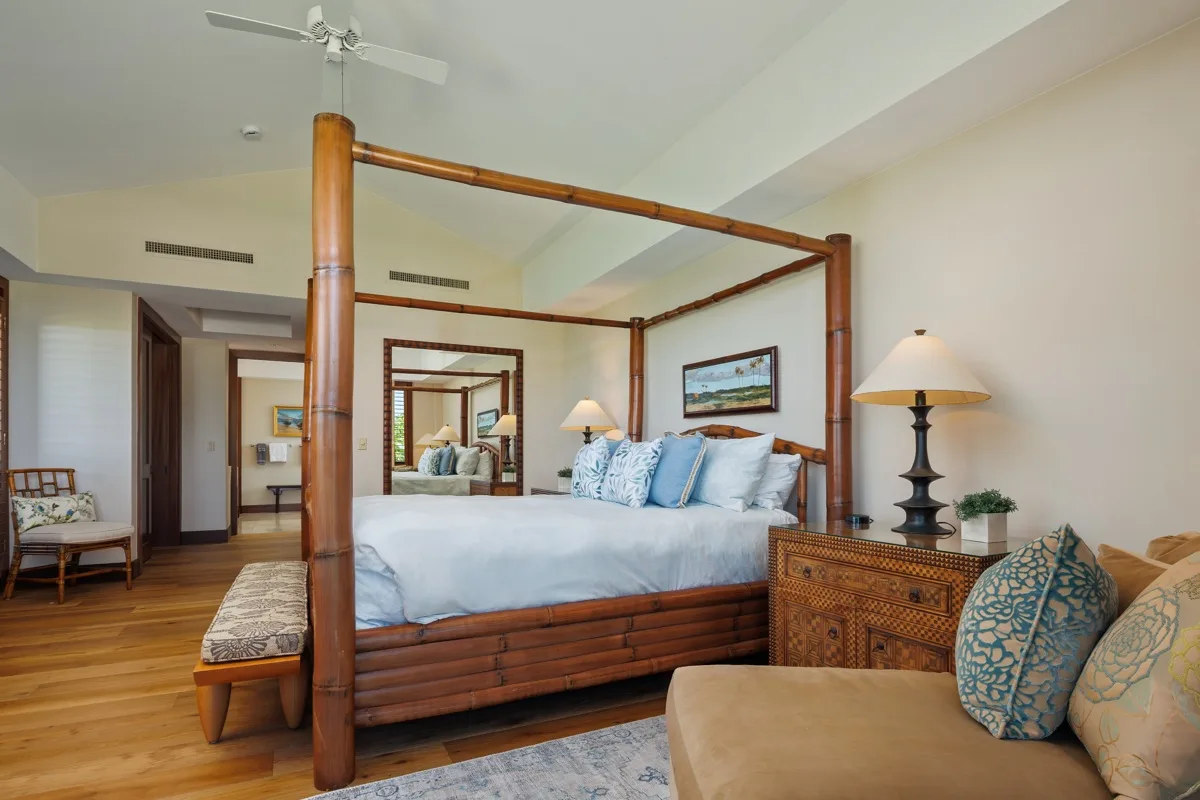 A bedroom with a wooden four-poster bed and a seating area.