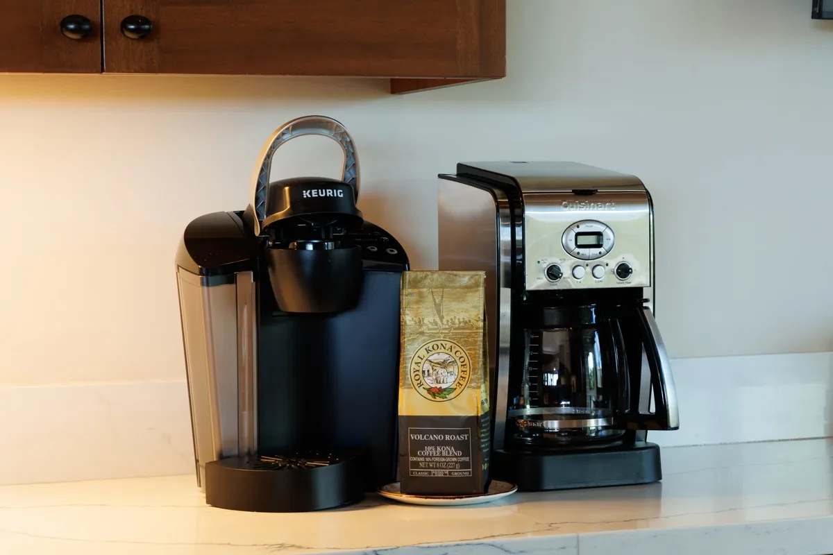 A kitchen counter with two coffee makers and a bag of coffee.