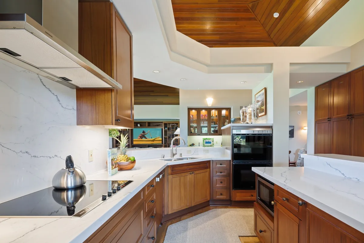 A spacious kitchen with wooden cabinetry, light countertops, and a wood-paneled ceiling.