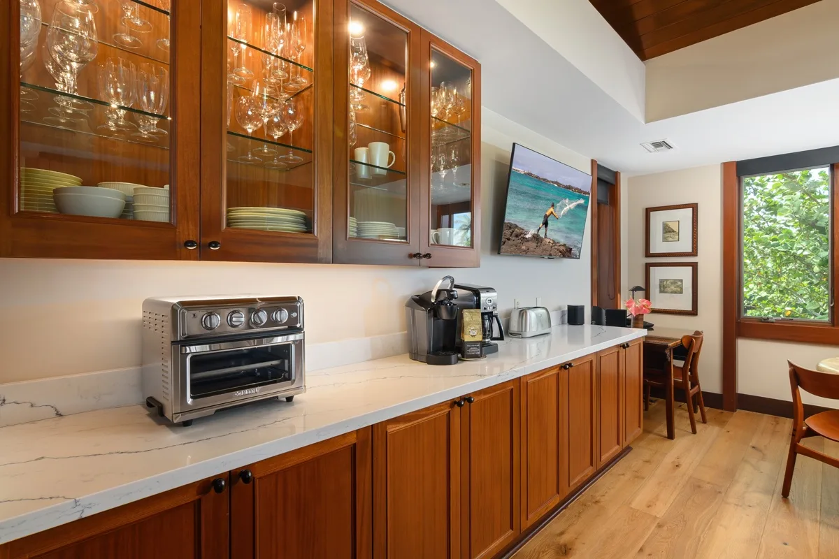 A kitchenette with wooden cabinets and countertop appliances beside a small dining area.
