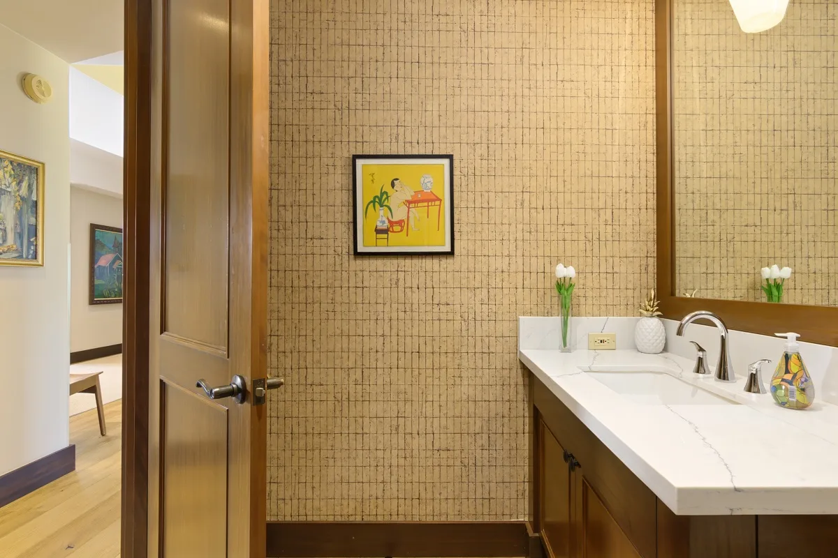 A bathroom vanity with a sink and framed artwork on the tiled wall.