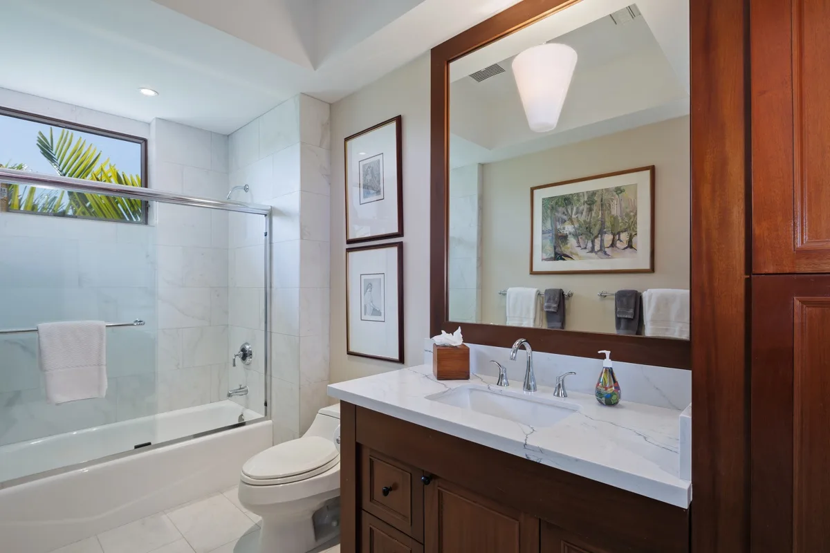 A bright bathroom with a bathtub, toilet, and wide vanity.