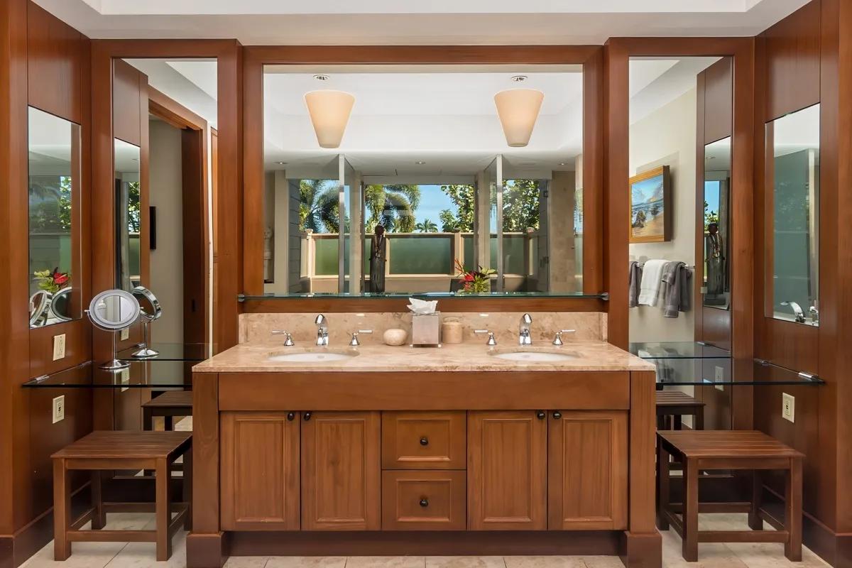 A bathroom vanity with a wide mirror, wooden cabinetry, and two sinks.