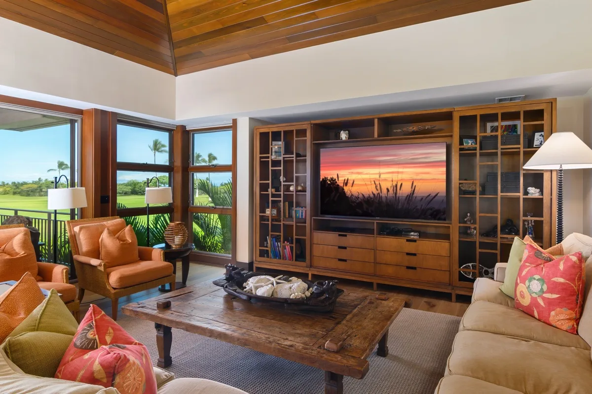 A living room with wood shelving around a television and seating around a coffee table.