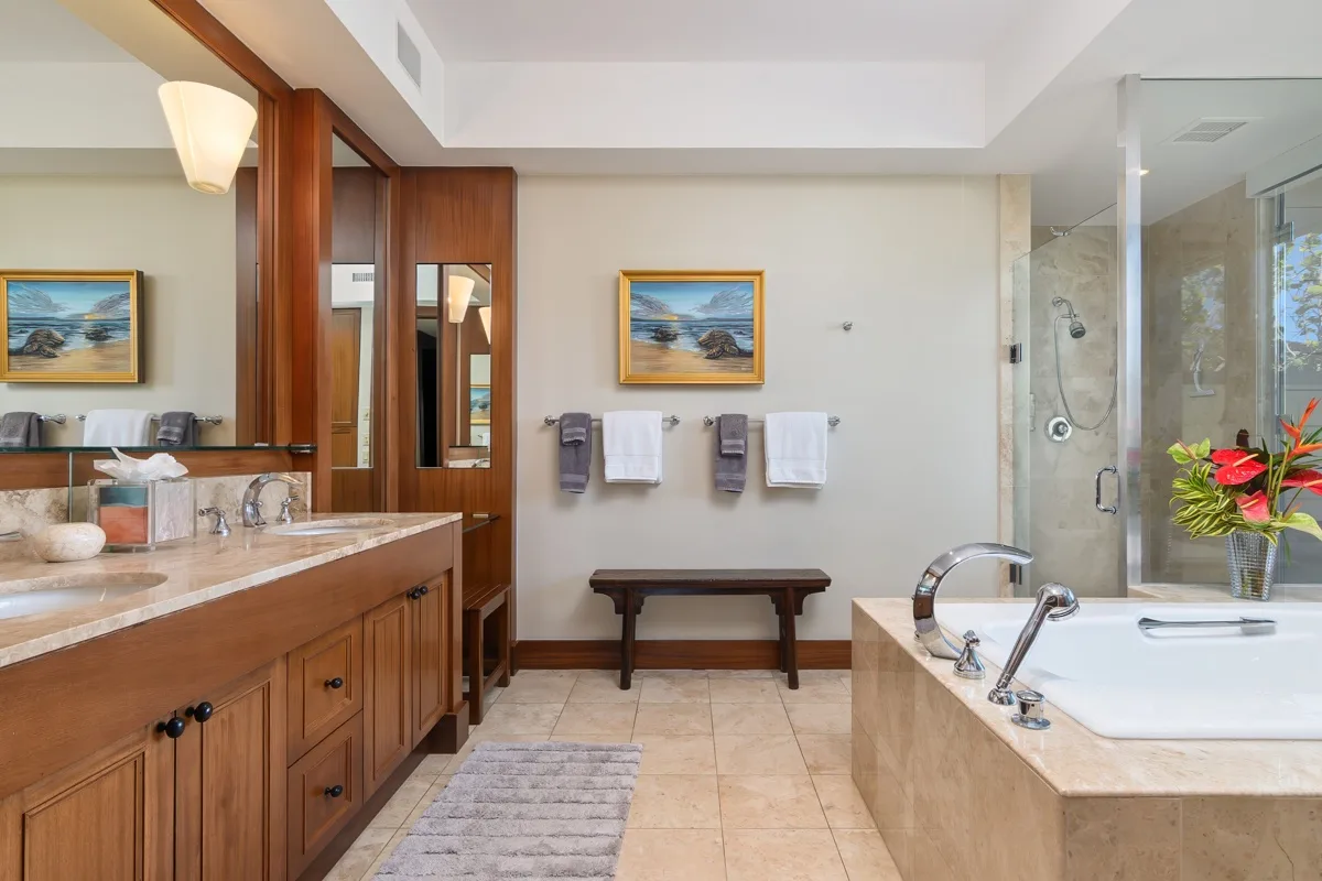A spacious bathroom with a double vanity, bathtub, and glass-enclosed shower.