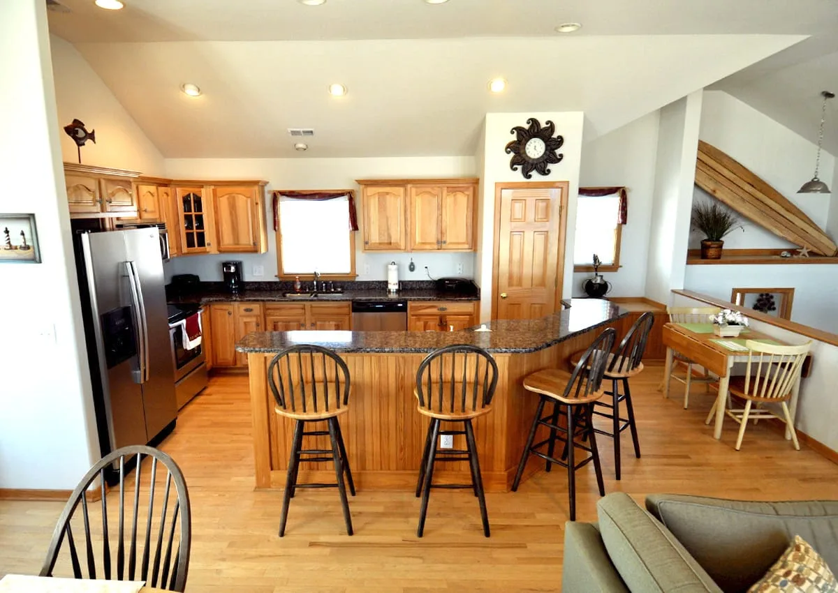 Una cocina y comedor abiertos con una isla central y gabinetes de madera.