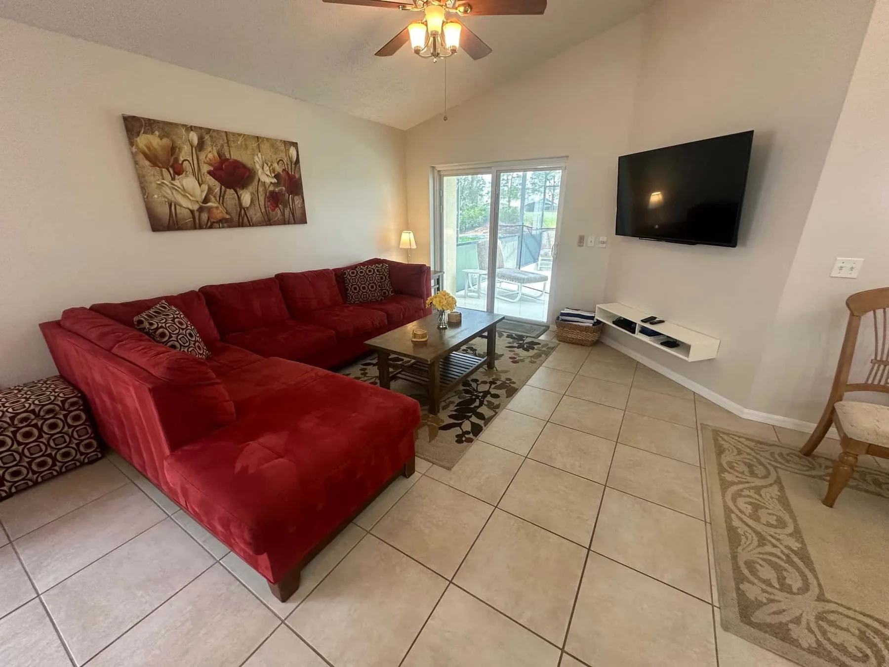 A living room with red seating, a coffee table, and a television.