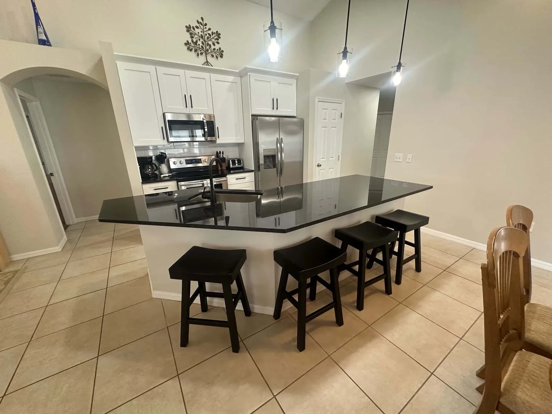 Una cocina luminosa con gabinetes blancos y una gran isla con asientos.