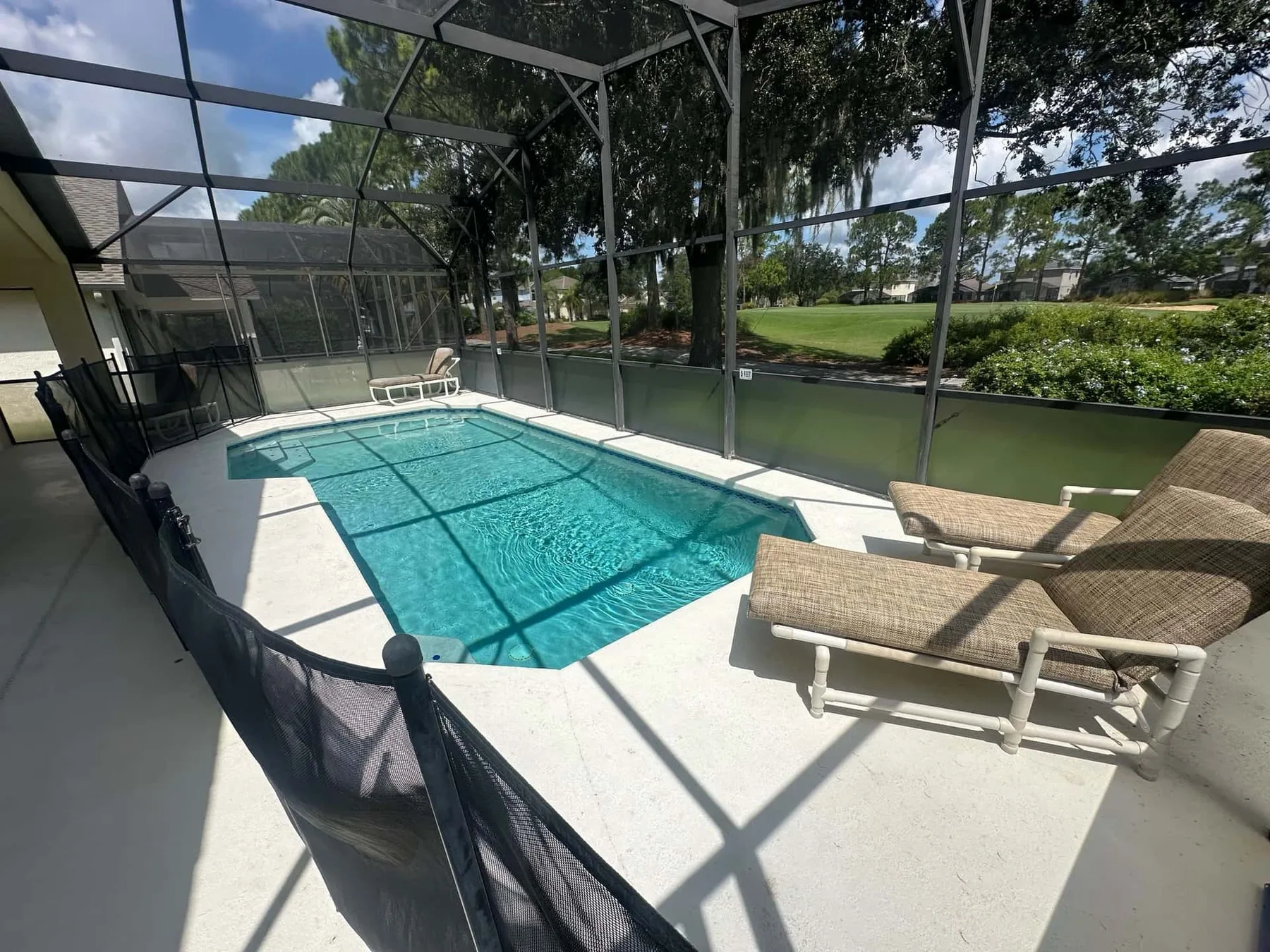 Una zona de piscina exterior con mosquiteros y asientos junto al agua.