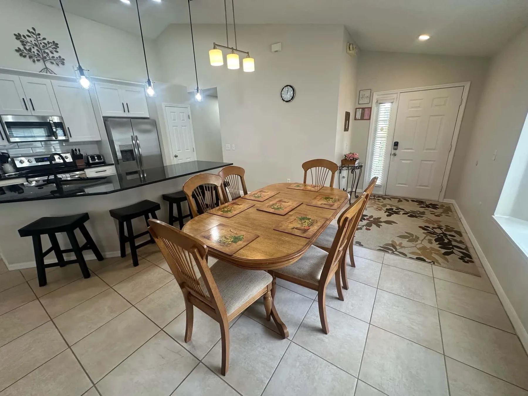 A dining area with a wooden table and chairs beside an open kitchen.