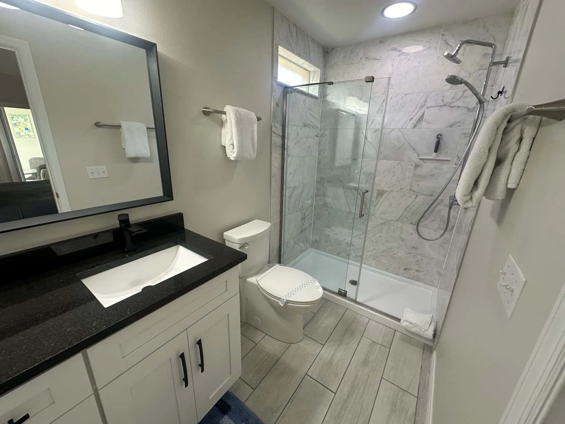 Un baño con lavabo, inodoro y ducha con paneles de vidrio.