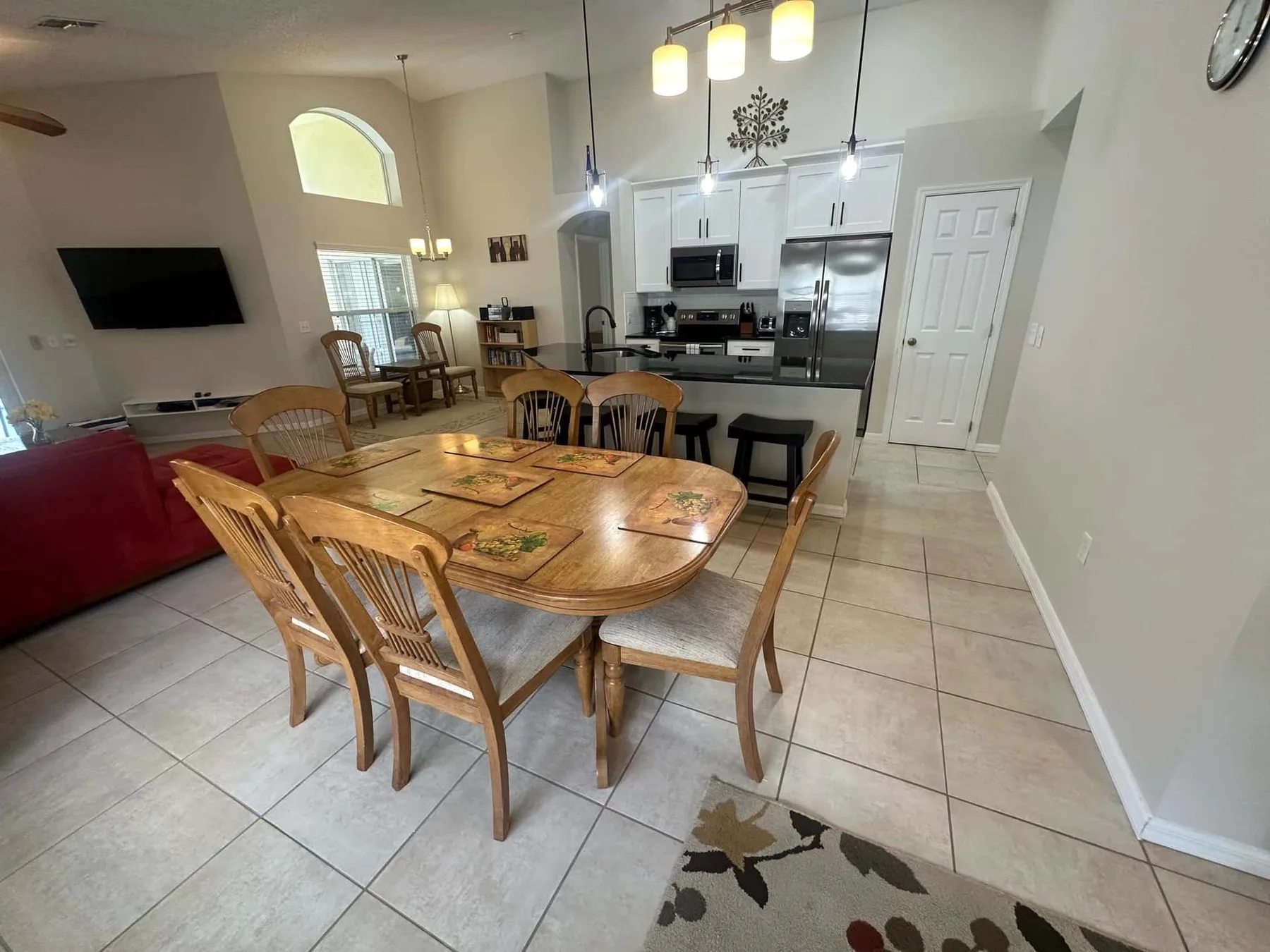 Un comedor abierto con cocina, mesa de madera y gabinetes blancos.
