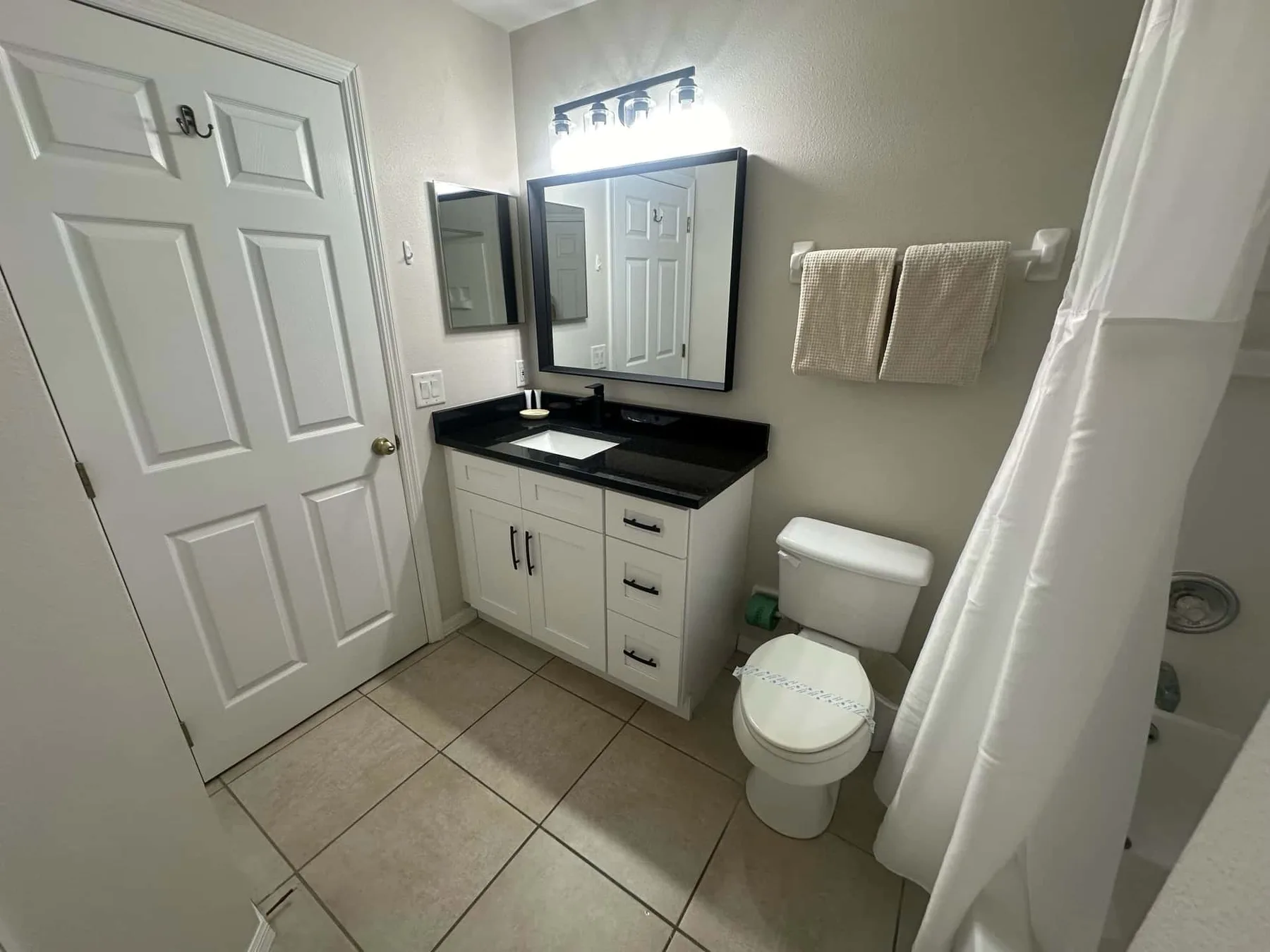 Un baño con lavabo, espejo, inodoro y cortina de ducha.