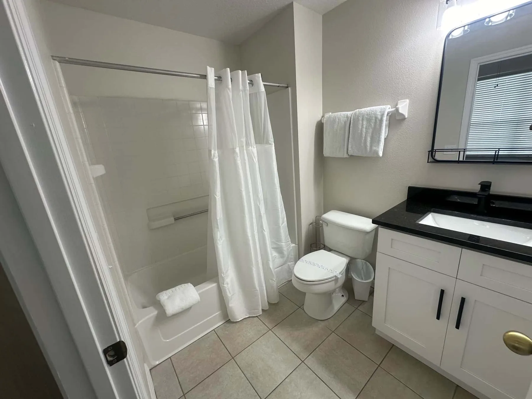 Un baño con bañera y cortina de ducha junto a un lavabo con mueble.