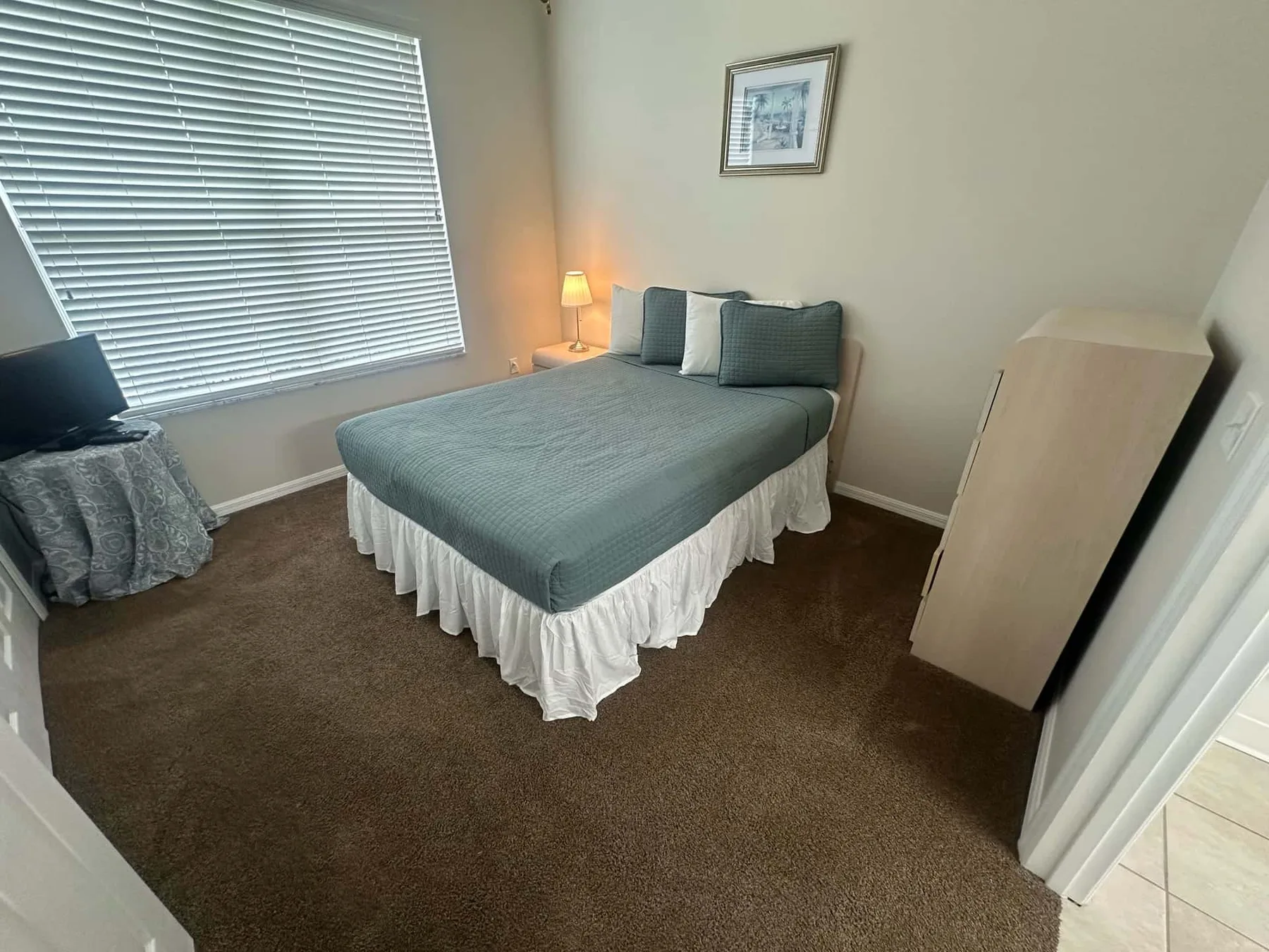 Un dormitorio con una cama tendida y una ventana con persianas.